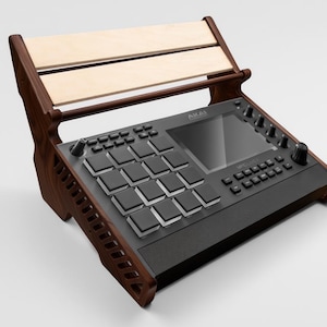 May include: A dark brown wooden stand with a light wood top, holding a black Akai MPC. The MPC has a screen, buttons, and pads. The stand is angled, with a modern design, and is suitable for music production.