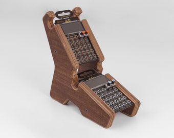 Könnte beinhalten: Ein Holzständer mit zwei kleinen elektronischen Geräten. Die Geräte haben ein Raster mit Knöpfen und einen kleinen Bildschirm. Der Ständer ist braun und hat eine natürliche Holzoptik.
