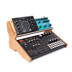 May include: A wooden stand with two tiers holds a black synthesizer with orange buttons and a blue synthesizer with the text "Big Sky".