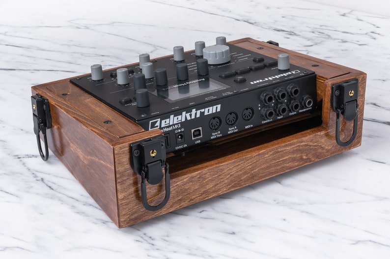 Peut inclure: Un bo&icirc;tier en bois avec des loquets et des poign&eacute;es noirs pour un synth&eacute;tiseur Elektron Heat MKII noir. Le bo&icirc;tier est en bois fonc&eacute; avec une finition naturelle.