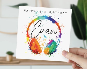 May include: A white card with the text "Happy 16th Birthday" and the name "Evan" written in black cursive. The card features a colorful illustration of headphones with musical notes and a rainbow paint splatter effect.