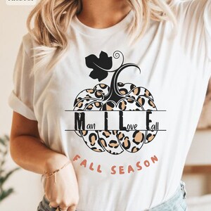 May include: White t-shirt with a leopard print pumpkin design. The pumpkin has a black stem and leaves. The text "Fall Season" is written below the pumpkin. The text "I love Fall" is written inside the pumpkin.
