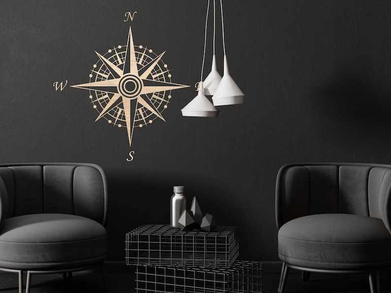 Puede incluir: Un dise&ntilde;o de br&uacute;jula negro y dorado en una pared negra con dos sillones negros y una mesa de metal negro con tapa de vidrio. El dise&ntilde;o de la br&uacute;jula tiene las letras N, S, E y W.