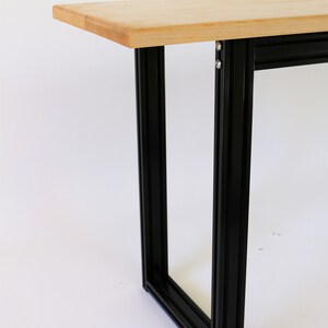 Puede incluir: Una mesa de madera con un marco de metal negro. La mesa est&aacute; hecha de madera clara y el marco est&aacute; hecho de metal negro.