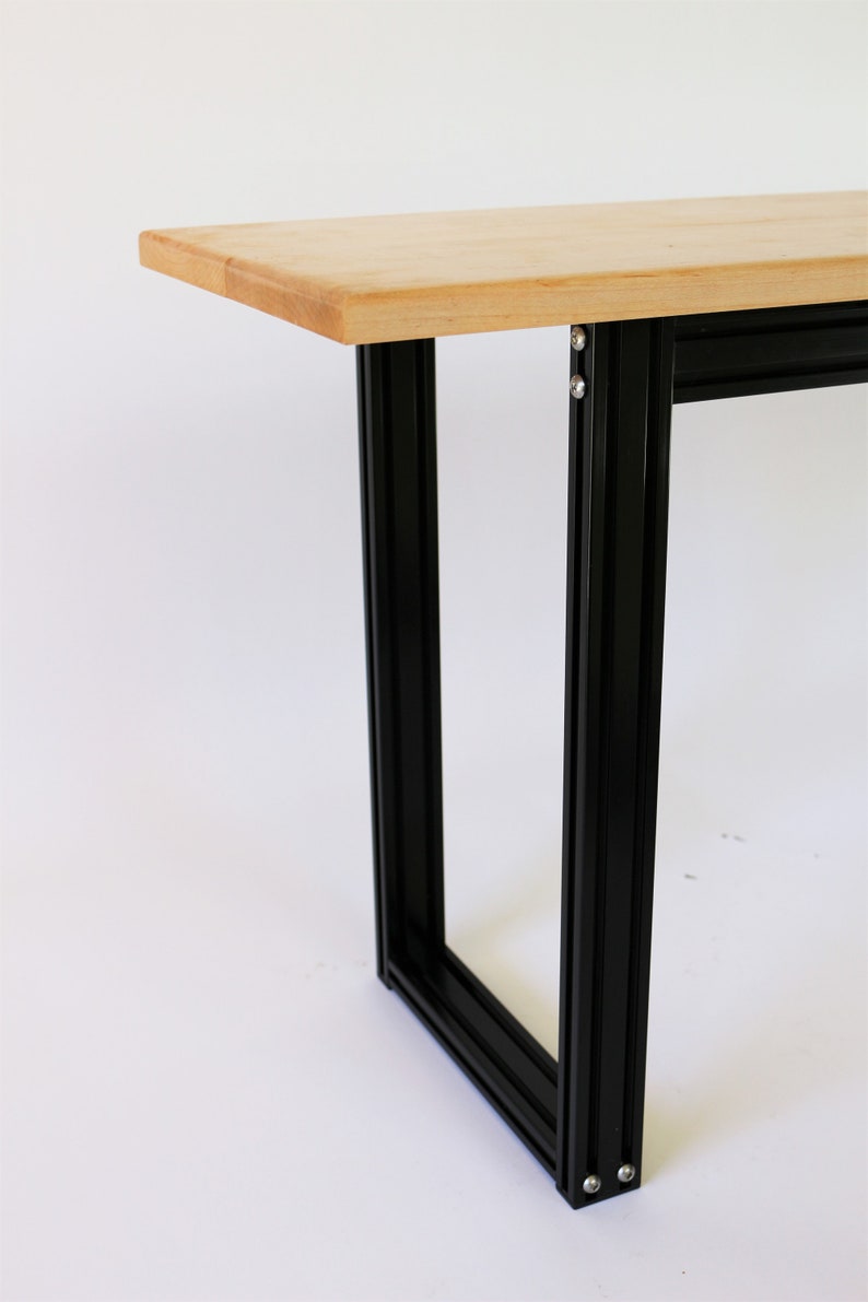 Puede incluir: Una mesa de madera con un marco de metal negro. La mesa est&aacute; hecha de madera clara y el marco est&aacute; hecho de metal negro.