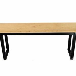 Puede incluir: Una mesa de madera larga y rectangular con un acabado de madera natural y patas de metal negro. La mesa est&aacute; sostenida por dos pares de patas, cada una con una forma rectangular.