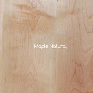 Puede incluir: Primer plano de una superficie de veta de madera marr&oacute;n claro con el texto "Maple Natural" impreso en blanco.