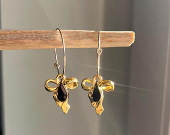 Creolen in Gold aus Edelstahl mit goldener Schleife und schwarzem tropfenförmigen Charm