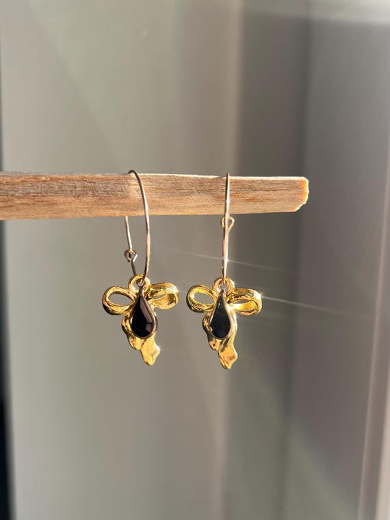 Hoop earrings in gold made of stainless steel with golden bow and black drop-shaped charm