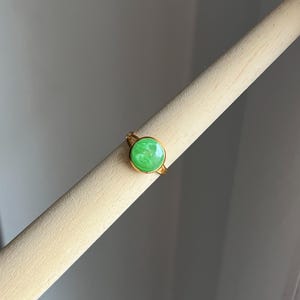 May include: A gold ring with a green stone. The stone has a marbled pattern.