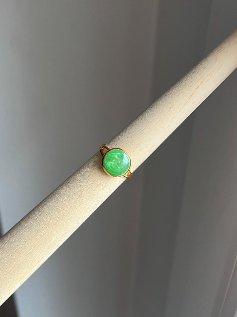 May include: A gold ring with a green stone. The stone has a marbled pattern.