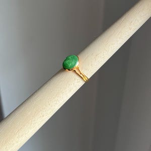 May include: A gold ring with a green oval-shaped gemstone.