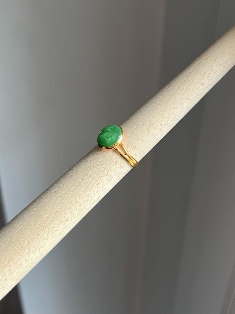 May include: A gold ring with a green oval-shaped gemstone.