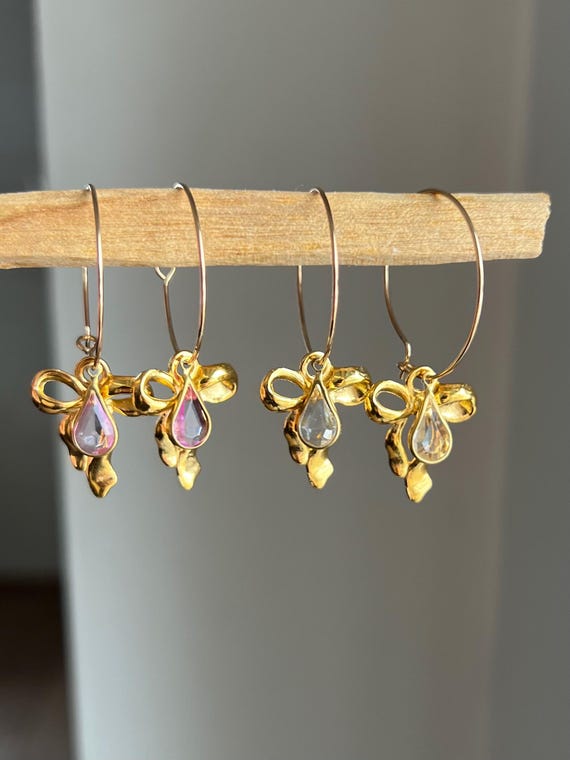 Hoop earrings in gold made of stainless steel with golden bows and drop-shaped charms in pink or transparent