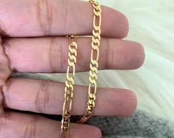 May include: A gold chain necklace with a curb link style. The chain is shown in a hand, with the ends of the chain overlapping.