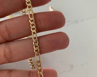 May include: A gold chain necklace with a classic figaro link design.