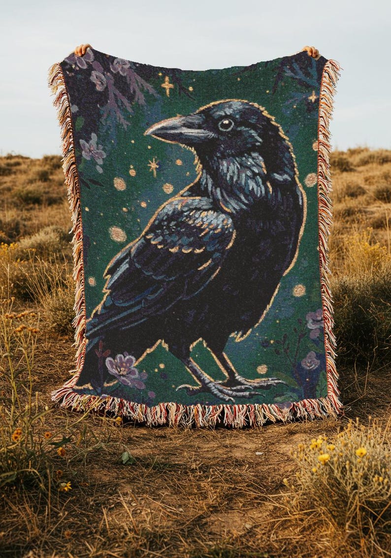 Raven woven blanket with a side profile of a raven with a yellow highlight around it a teal background and flowers in the corners witchy tapestry