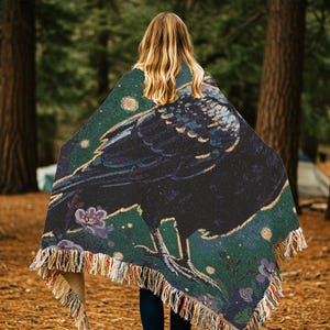 Raven woven blanket with a side profile of a raven with a yellow highlight around it a teal background and flowers in the corners witchy tapestry