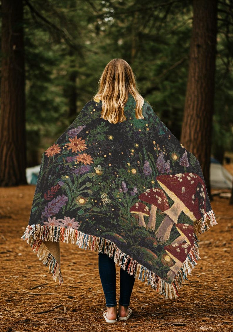 Woven blanket with a enchanted woodland whimsy scene with toadstool mushrooms wildflowers fireflies moths and trees nighttime scene cottagecore witchy tapestry