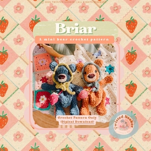 May include: Two crocheted bear dolls, one blue and one orange, are featured in this image. They are wearing hooded scarves and holding small crocheted strawberries. The background includes a patchwork blanket and a pink and white strawberry pattern.
