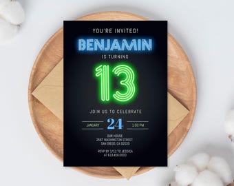 Puede incluir: Una tarjeta de invitación negra con texto azul y verde neón, sobre un plato de madera con un sobre marrón. La tarjeta dice "YOU'RE INVITED! BENJAMIN IS TURNING 13." Detalles de fecha, hora y lugar.