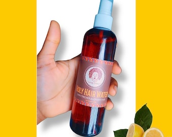 May include: A brown glass bottle with a spray nozzle and a label that reads "Holy Hair Water" with the text "Gain Thicker & Longer Hair" below. The label also features a logo with a woman's face and the text "Long Glory".