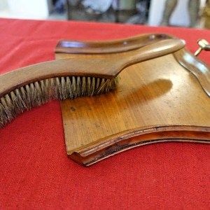Peut inclure: Un ensemble de balayette et pelle en bois avec une poignée en laiton. La pelle est en forme de croissant de lune et a un bord décoratif. La brosse est faite de poils naturels et a un manche en bois.