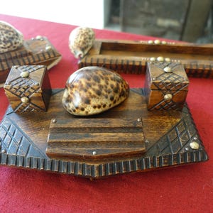 Peut inclure: Ensemble d'accessoires de bureau en bois faits à la main, comprenant un porte-stylo, un plateau et de petites boîtes. Les pièces sont en bois foncé et présentent des sculptures décoratives et des accents de coquillages. Les articles sont disposés sur une surface rouge.