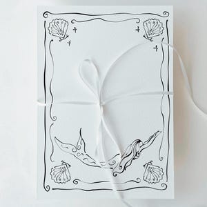 Pu&ograve; includere: Biglietto bianco con un disegno a tratto nero di una sirena e conchiglie. Il biglietto &egrave; legato con un nastro bianco. L'illustrazione della sirena &egrave; centrata.
