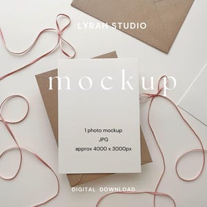Mockup di biglietto color crema 5x7 stravagante con busta in carta kraft e fiocchi di nastro rosa / Immagine in stile flatlay di invito
