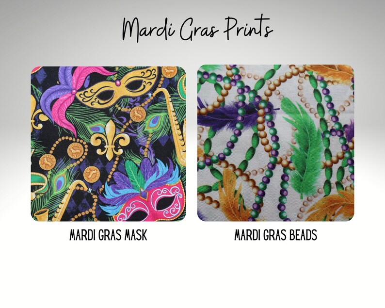 May include: Two fabric prints featuring Mardi Gras themes. The first print is black with purple, green, gold, and pink accents. It features Mardi Gras masks, feathers, fleur-de-lis, and beads. The second print is white with gold, green, and purple accents. It features Mardi Gras beads and feathers.