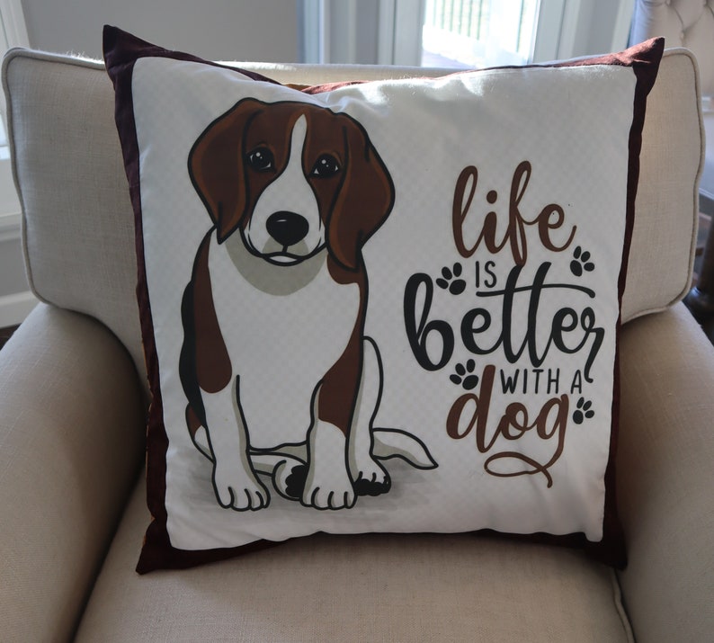 Pu&ograve; includere: Un cuscino bianco con un'illustrazione di un beagle marrone e bianco e il testo "life is better with a dog".