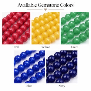 May include: A collection of round gemstone beads displayed in five color variations labeled Available Gemstone Colors. The colors include red, yellow, green, blue, and navy. Each section shows multiple rows of smooth, polished spherical beads.