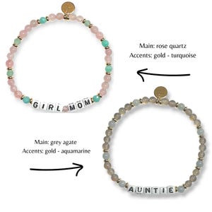 May include: Two beaded bracelets. One features rose quartz beads, turquoise accents, and the word "GIRL MOM". The other bracelet has grey agate beads, aquamarine accents, and the word "AUNTIE". Both bracelets have gold-colored accents.