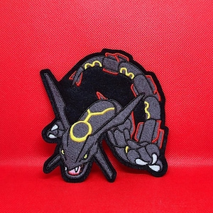 May include: Embroidered patch featuring a stylized black and gray dragon with yellow and red accents. The dragon has a detailed design with sharp features and is set against a red background. This patch is suitable for jackets, bags, or other fabric items.