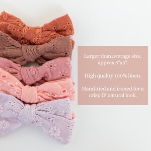 May include: Four handmade linen hair bows in shades of pink, peach, and brown. Each bow is approximately 5 inches by 3 inches and features a delicate eyelet pattern.