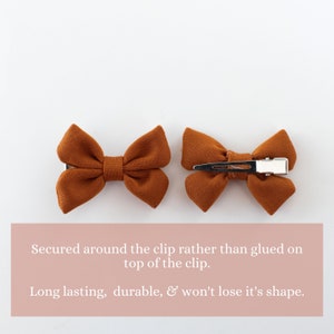 May include: Two brown fabric hair bows with metal clips. The bows are secured around the clip rather than glued on top of the clip.  "Secured around the clip rather than glued on top of the clip. Long lasting, durable, & won't lose it's shape."