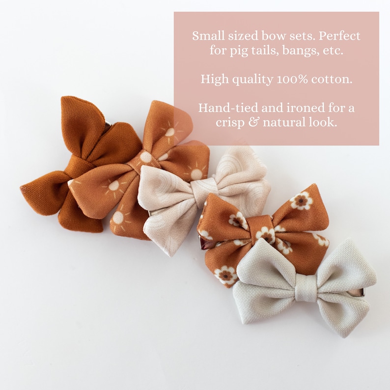 May include: Set of four small fabric hair bows. Two bows are brown with a sun pattern, one is beige with a swirl pattern, and one is beige with a floral pattern. The bows are hand-tied and ironed for a crisp look.