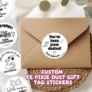 May include: A set of round white stickers with black text and graphics, including phrases like You've been pixie dusted, Bon Voyage, and A little Pixie Dust at sea, featuring icons of a wand, a duck, and stars, applied to a brown paper envelope.
