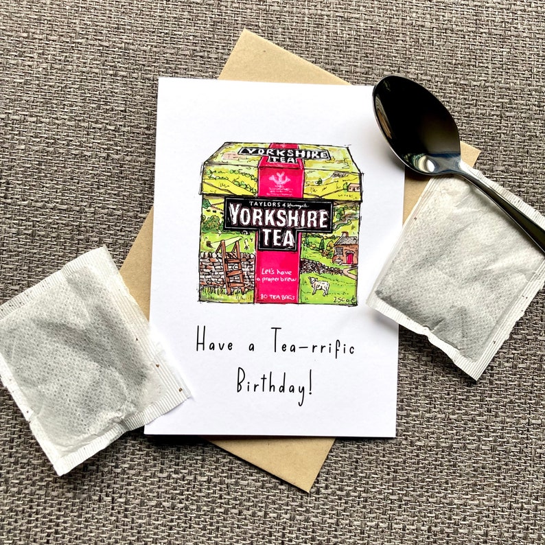 May include: A birthday card with a hand-drawn illustration of a box of Yorkshire Tea. The box is yellow with a red and white label. The text on the card reads "Have a Tea-rrific Birthday!"