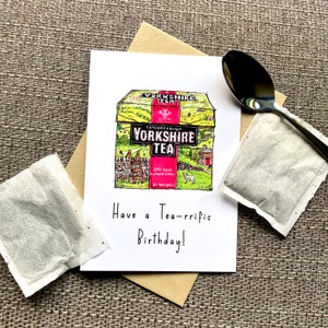 May include: A birthday card with a hand-drawn illustration of a box of Yorkshire Tea. The card reads "Have a Tea-rrific Birthday!"