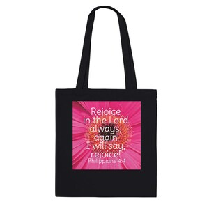 Puede incluir: Bolsa de tela negra con un diseño de flor rosa y el texto "Regocijaos en el Señor siempre; otra vez digo: ¡Regocijaos! Filipenses 4:4".