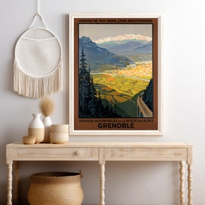 May include: Vintage travel poster advertising a trip to Grenoble, France. The poster features a scenic view of the French Alps with a winding road leading to the city. The text on the poster reads "Chemins de Fer Paris, Lyon, Mediterranee" and "Services Automobiles de la Route des Alpes Grenoble".