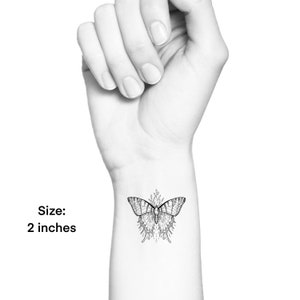 May include: Black and white line art temporary tattoo of a butterfly with floral accents. Size: 2 inches.