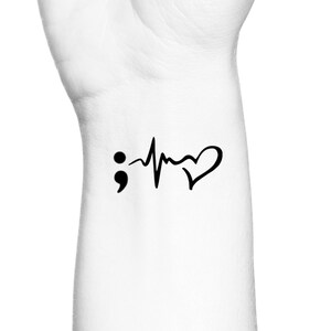 May include: Black and white temporary tattoo featuring a semicolon, a heartbeat, and a heart.