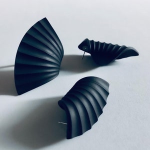 Pode incluir: Três brincos pretos, geométricos, em forma de leque com textura estriada.
