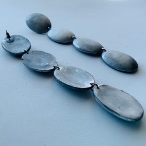 May include: A pair of long silver earrings with multiple oval-shaped beads connected by silver rings.