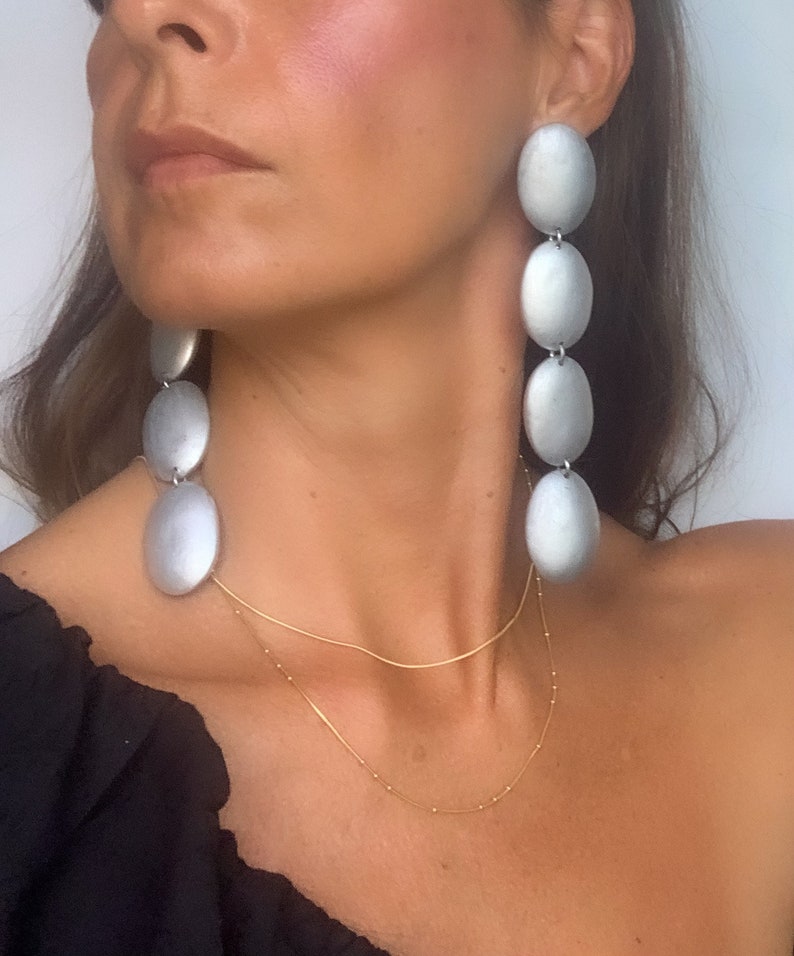 May include: Silver tone long drop earrings with multiple oval shaped links. The earrings are a statement piece and would be a great addition to any jewelry collection.