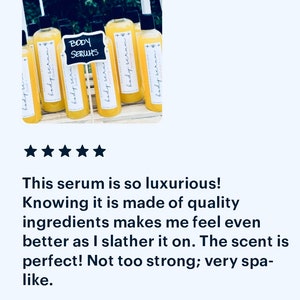 May include: A group of eight amber glass bottles with yellow liquid and white labels that say "body serum". The bottles are arranged on a wooden surface. A black chalkboard sign says "BODY SERUMS".