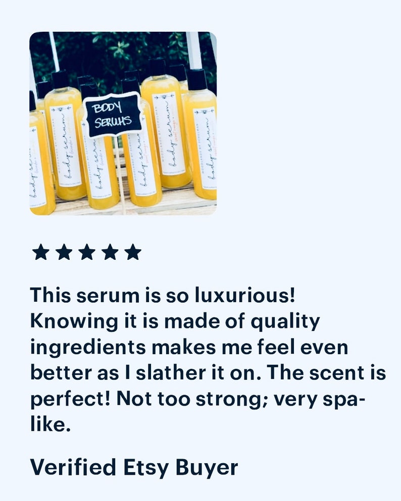 May include: A group of eight amber glass bottles with yellow liquid and white labels that say "body serum". The bottles are arranged on a wooden surface. A black chalkboard sign says "BODY SERUMS".